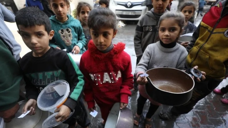 Children with empty pots wait as aid workers distribute food in Gaza City earlier this month.jpeg